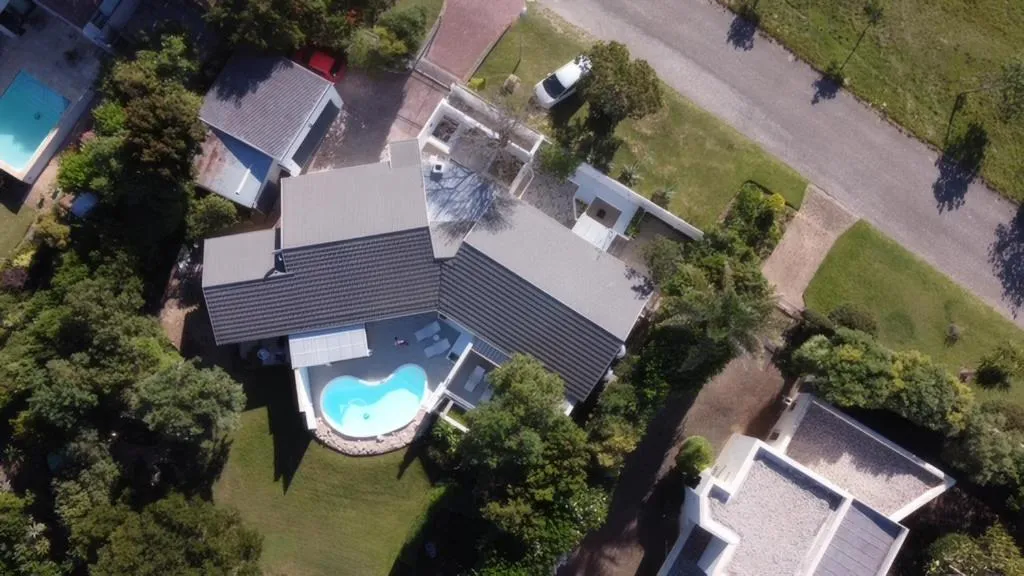 Aerial view of the property's roofline, kidney-shaped pool, and garden layout