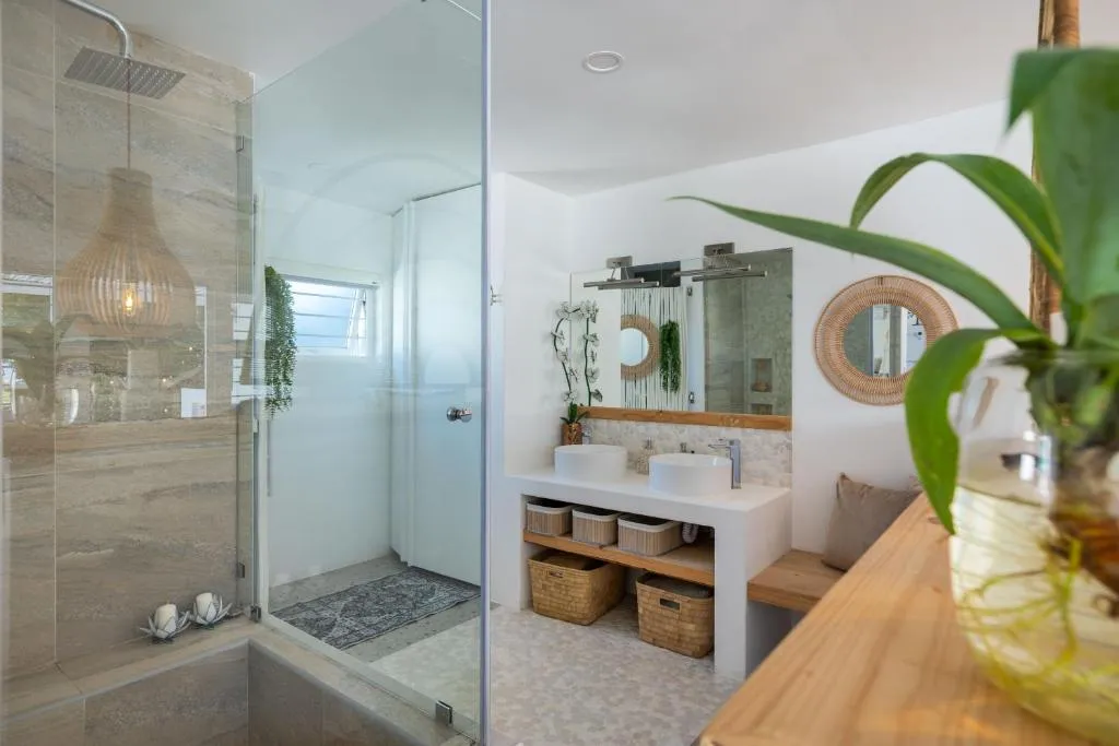 Bathroom with a double vessel-sink vanity, walk-in shower, and woven mirror