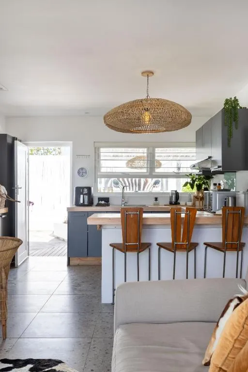 Kitchen bar with a rattan pendant light and three wooden stools