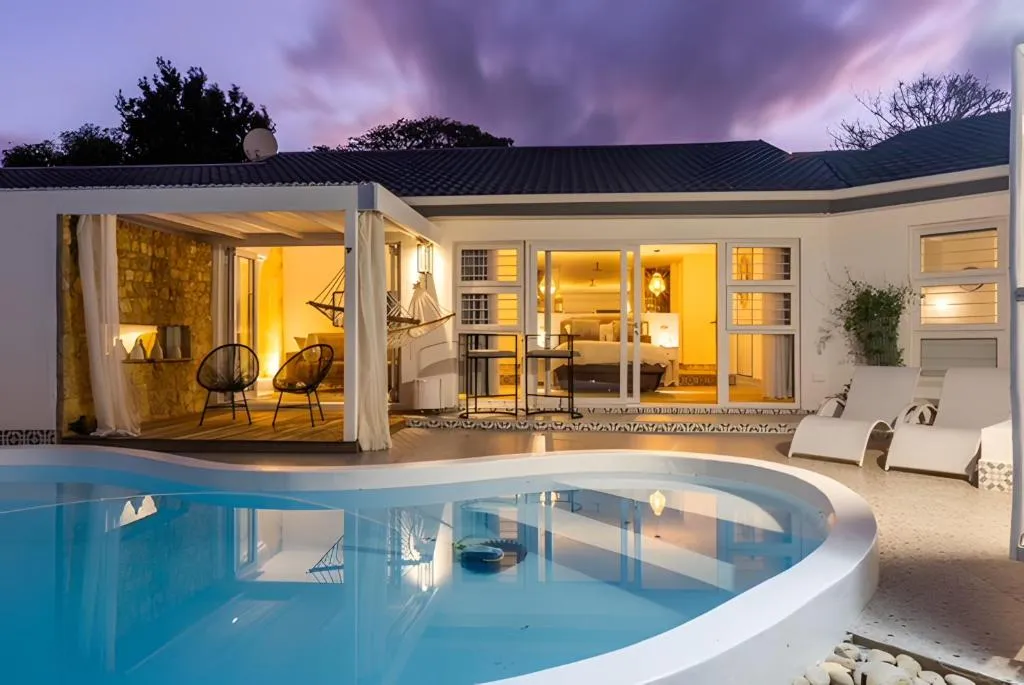 Twilight view of the pool and covered patio hammock with the lit interior beyond