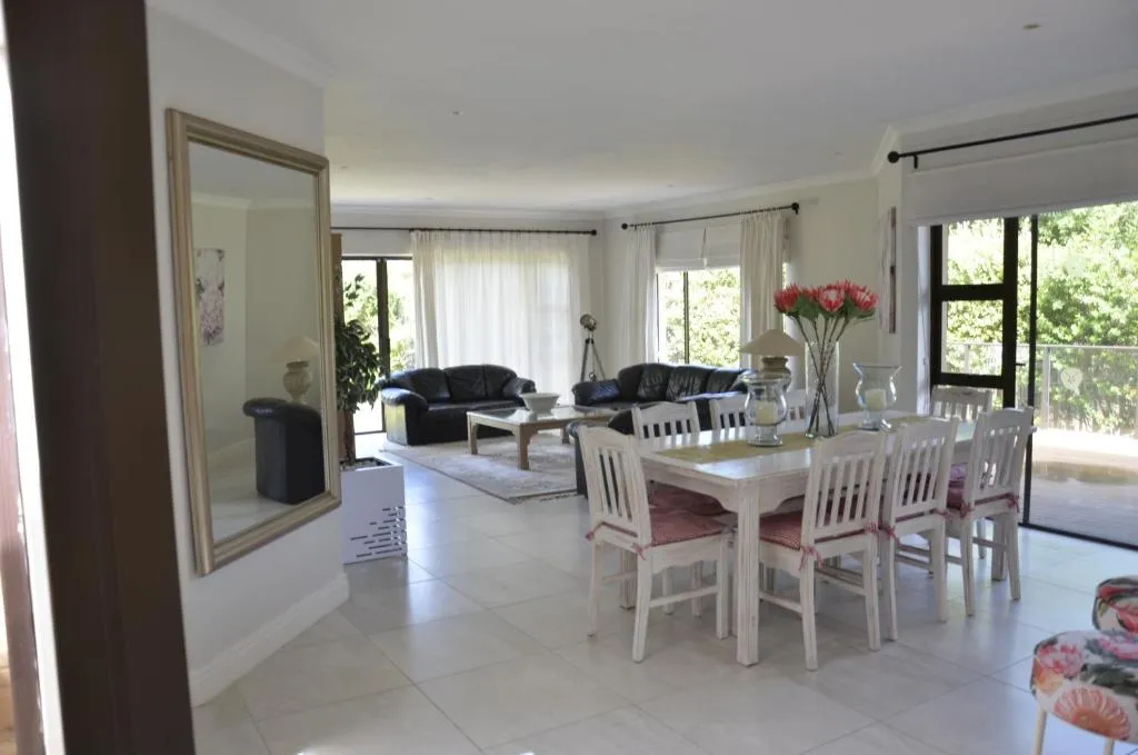 Dining table for eight beside a mirrored entrance, with the lounge visible beyond