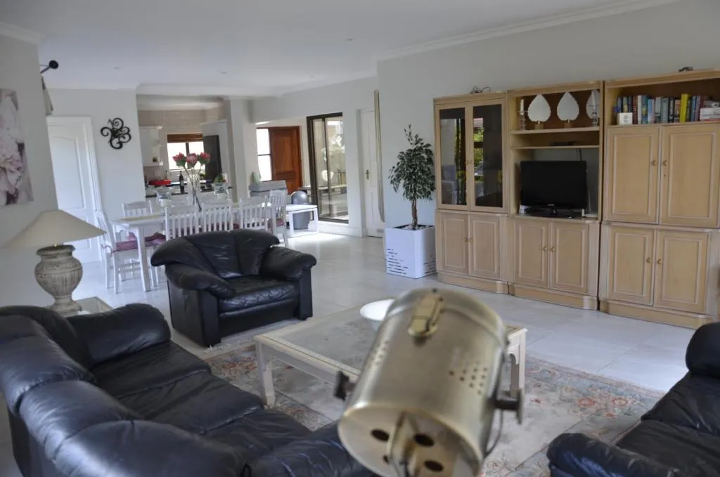 Open-plan living and dining area with black leather sofas leading through to the kitchen