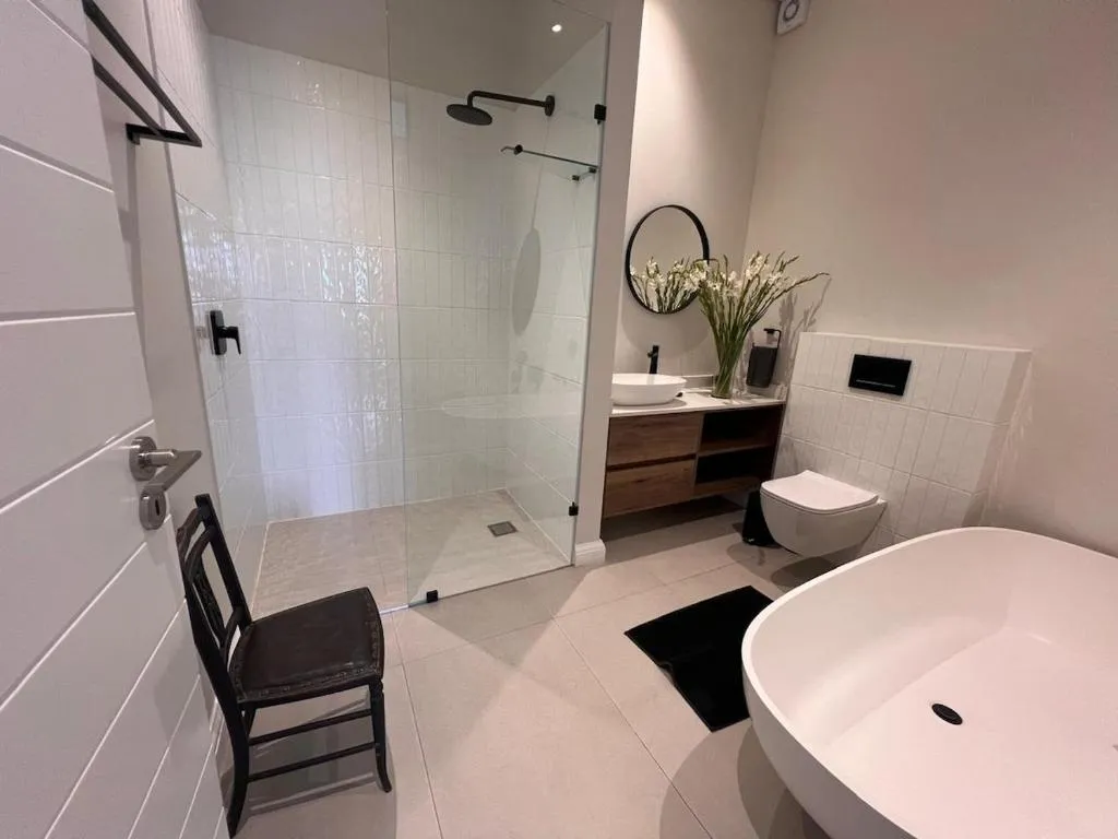 Bathroom with a freestanding oval tub, walk-in glass shower, and round black-framed mirror