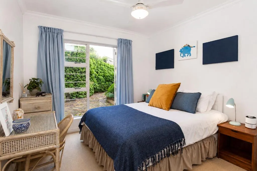 Second bedroom in navy and mustard tones with a door onto a small brick-paved courtyard