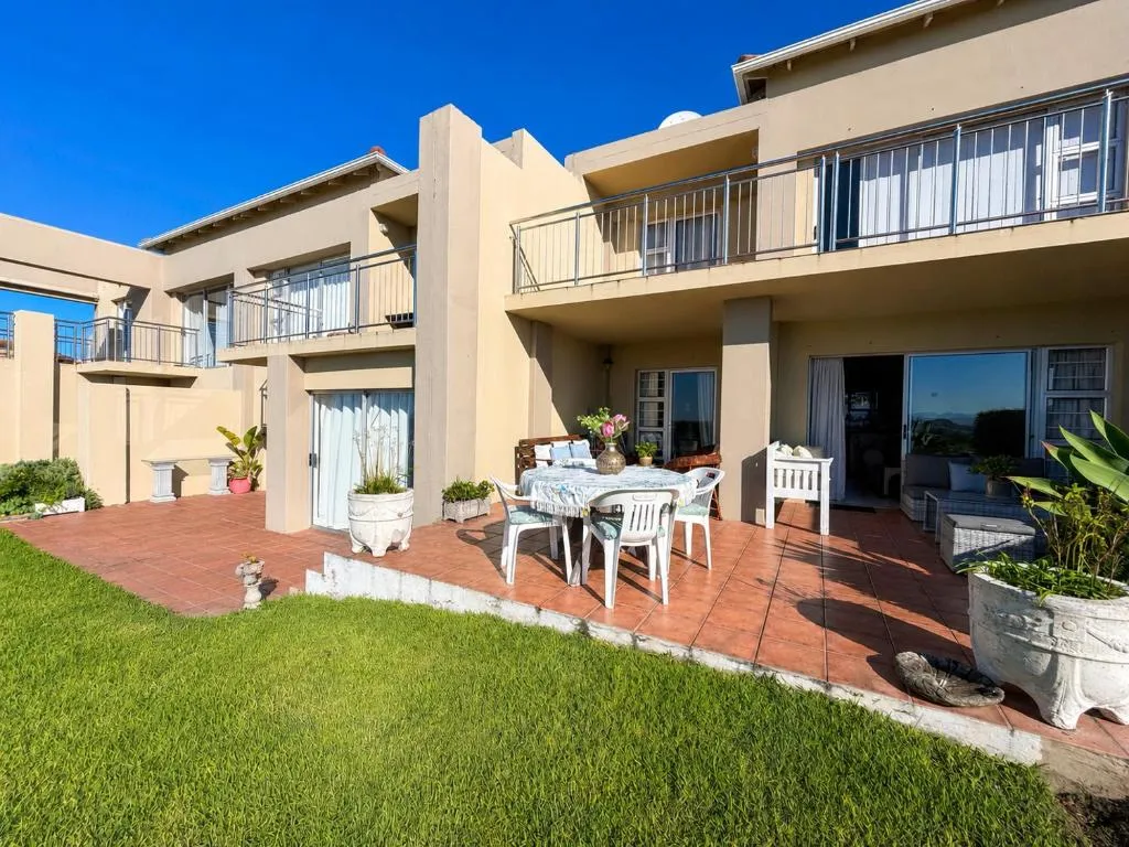 Double-storey unit exterior with a paved patio, outdoor dining table and upper-floor balconies