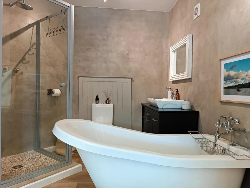 Bathroom with a freestanding tub, separate glass shower and framed harbour print