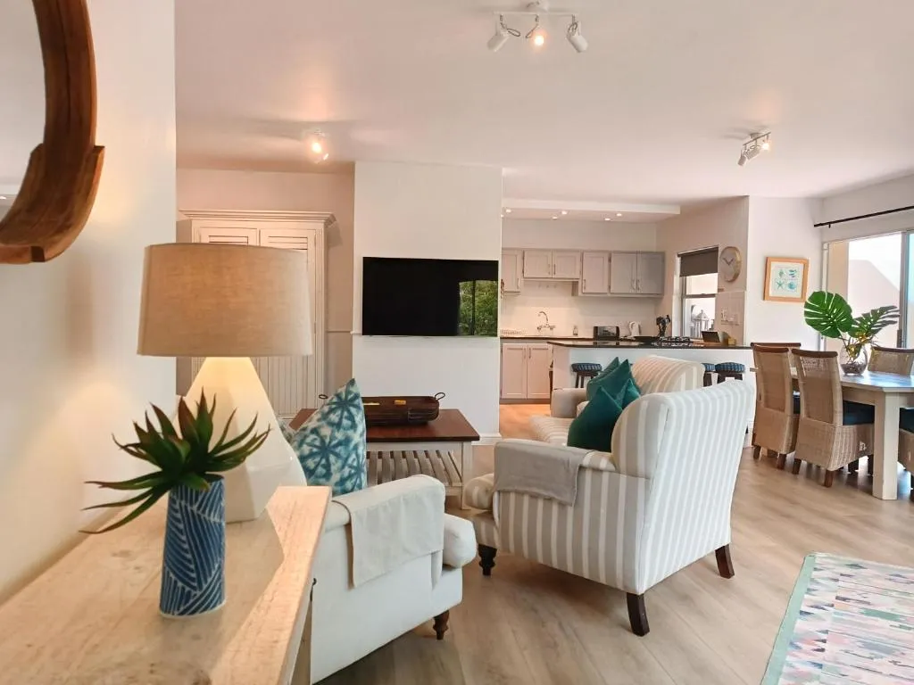 Open-plan living room with striped armchairs and a view through to the kitchen and dining table