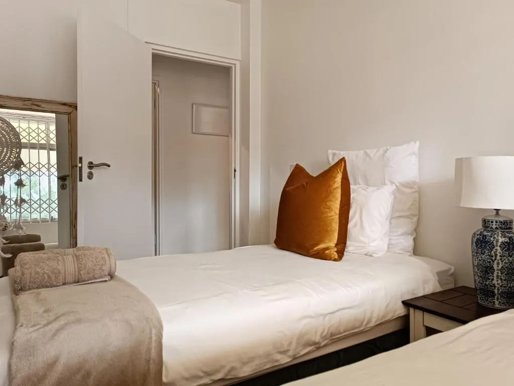 Second bedroom with twin beds, a mustard velvet cushion and a security-gated door