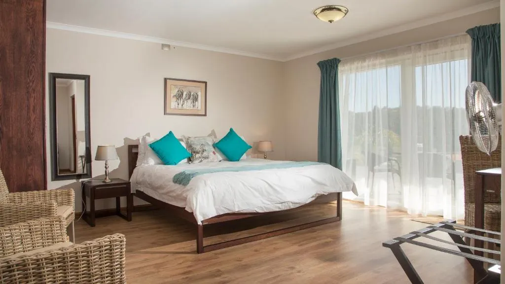Bedroom with teal cushions, wooden furniture and sliding doors onto a balcony