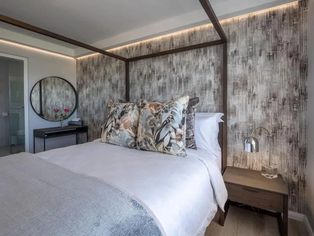 Bedroom with a four-poster bed frame against a textured metallic feature wall