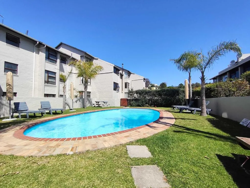 Shared estate swimming pool with palm trees and loungers between the apartment blocks