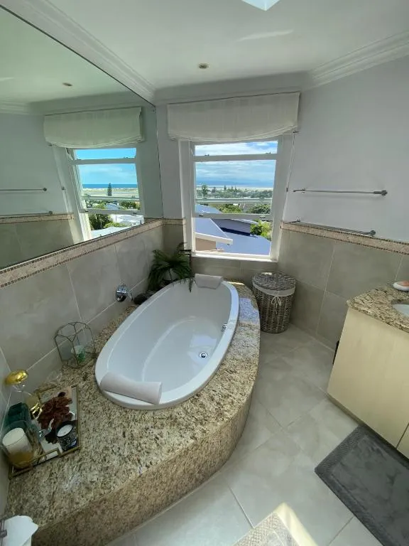 Bathroom with an oval soaking tub on a granite plinth and a window framing the sea