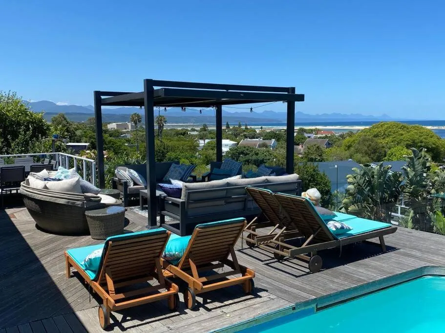 Rooftop lounge deck with a pergola, wicker daybed and sofa seating overlooking the coast
