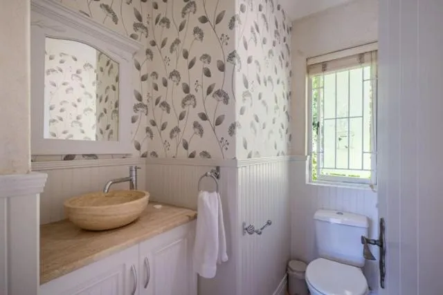 Powder room with floral wallpaper, a stone vessel basin and a leaded window