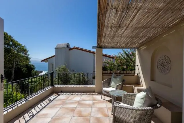 Reed-shaded terrace with wicker seating and a distant sea view past the neighbouring rooftop