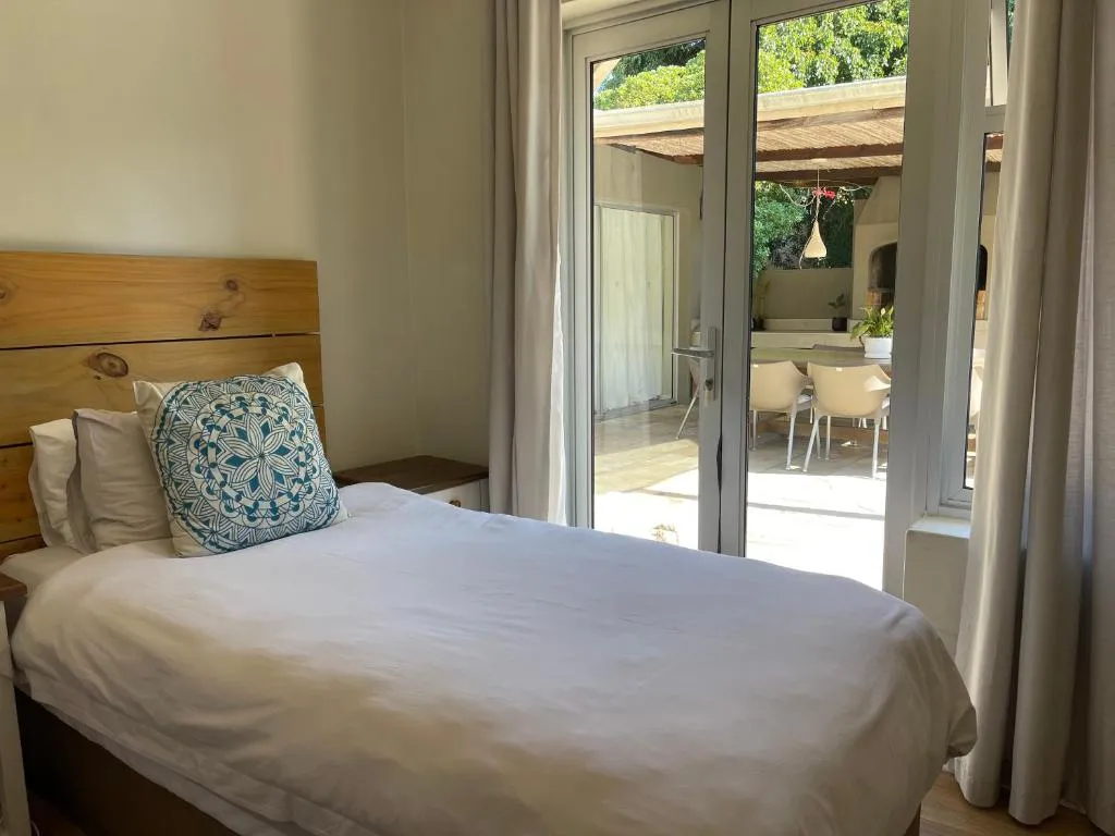 Bedroom with a wood headboard and glass doors opening onto a covered patio dining area