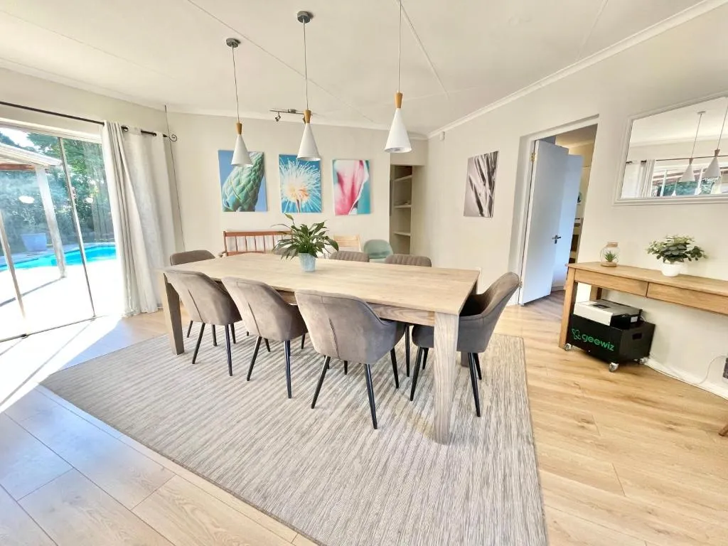 Dining room with a long wood table seating ten and sliding doors open to the pool