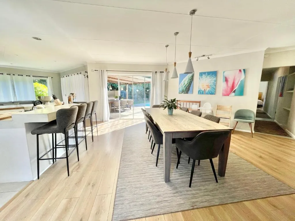 Open-plan kitchen with a long bar counter and dining area opening onto the pool patio