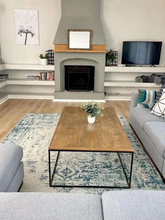 Living room with a stone-mantled fireplace, built-in shelving and a wall-mounted TV