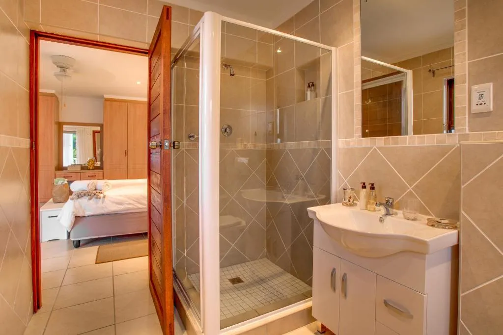 Ensuite bathroom with glass shower cubicle and a view through to the bedroom