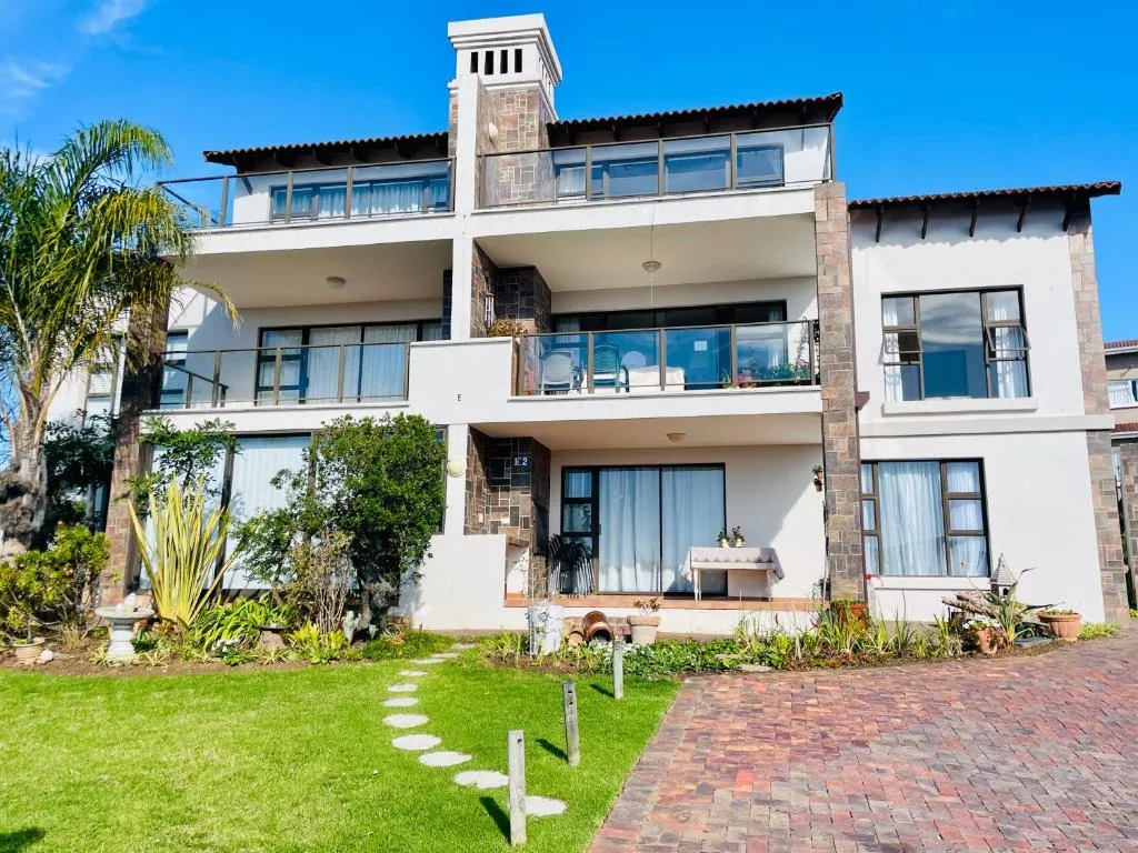 Exterior of the double-storey apartment block with a palm tree and paved garden path