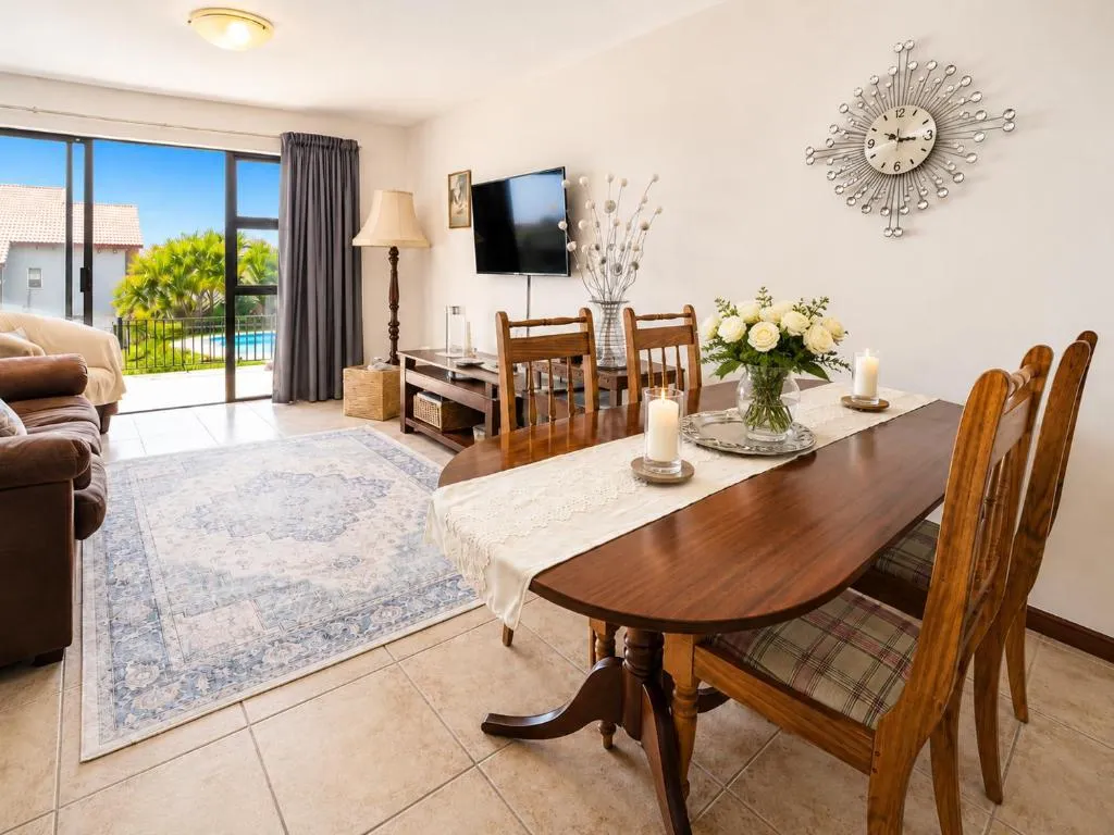Dining table beside the living room with a glimpse of the pool through sliding doors