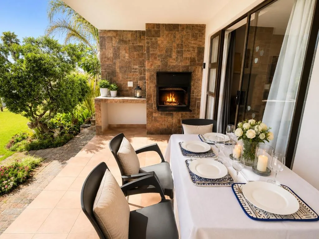 Covered patio with a built-in braai fireplace and a table set for outdoor dining