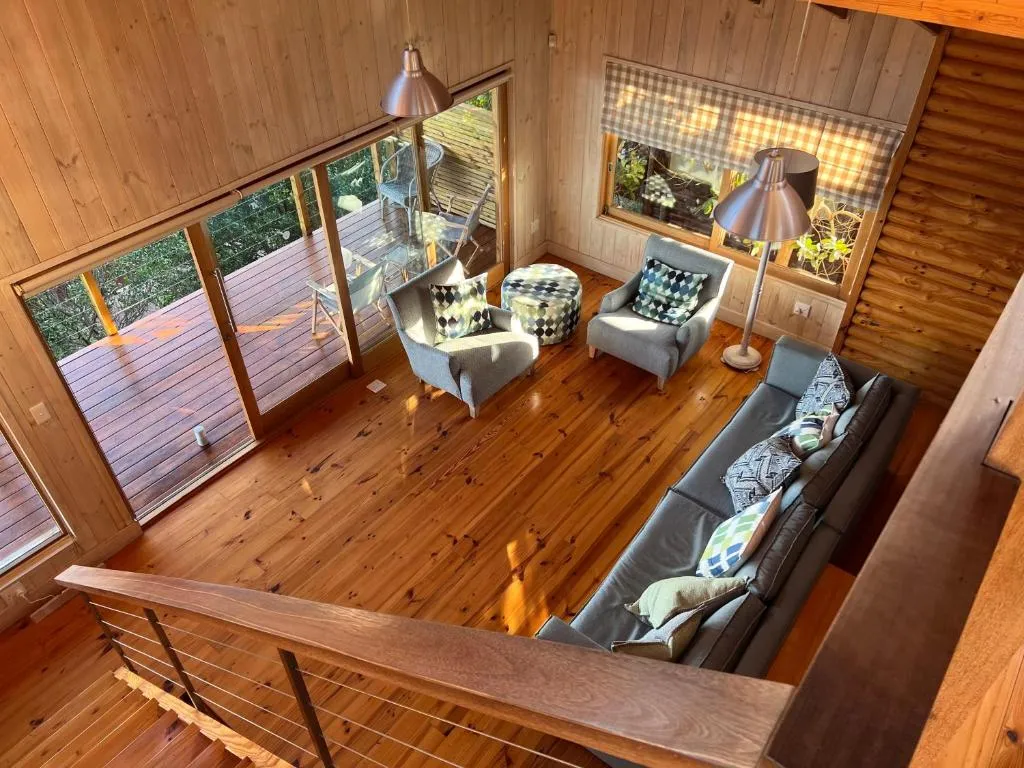Mezzanine lounge with armchairs and pouf overlooking the double-height living room below