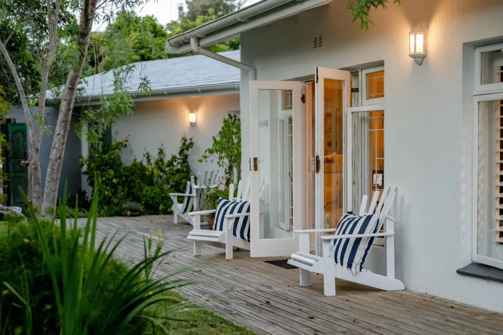 Evening view of the guest house exterior deck with striped-cushion chairs and lit doorways