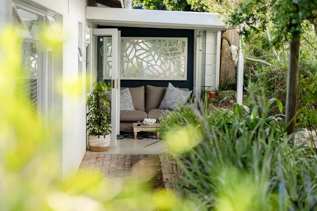 Garden reading nook with a sofa and decorative screen tucked beside a brick pathway