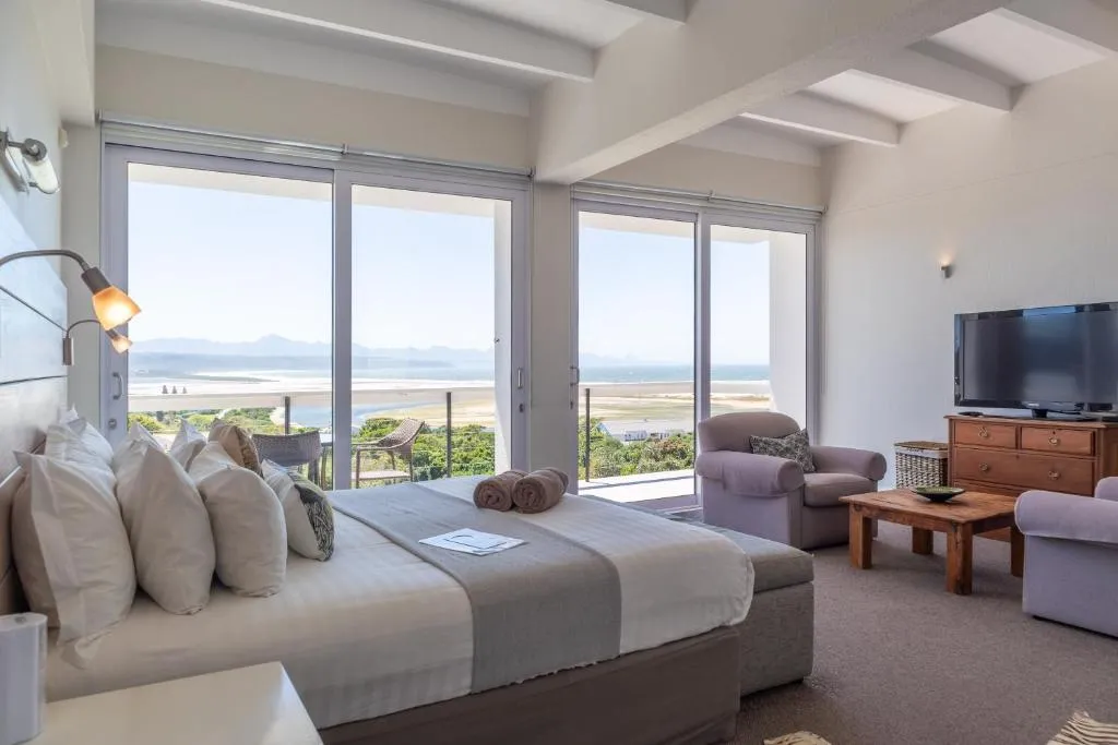 Bedroom with sliding doors onto a balcony overlooking the estuary, beach, and mountains