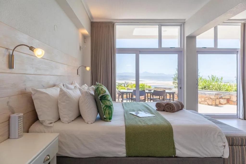 Bedroom with a wood-panel headboard and sliding doors onto an outdoor dining terrace with sea view