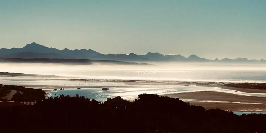 Misty morning view over lagoon sandbanks and boat channels to mountains in the distance