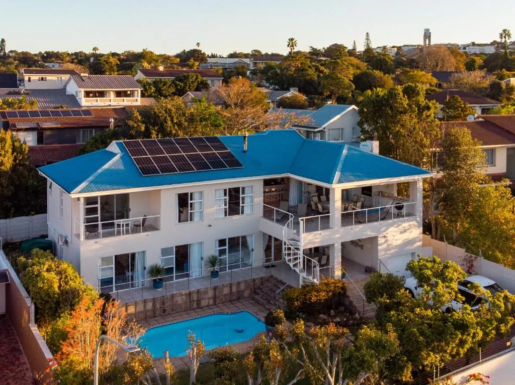 Aerial view of the double-storey house with solar roof panels and a curved garden pool