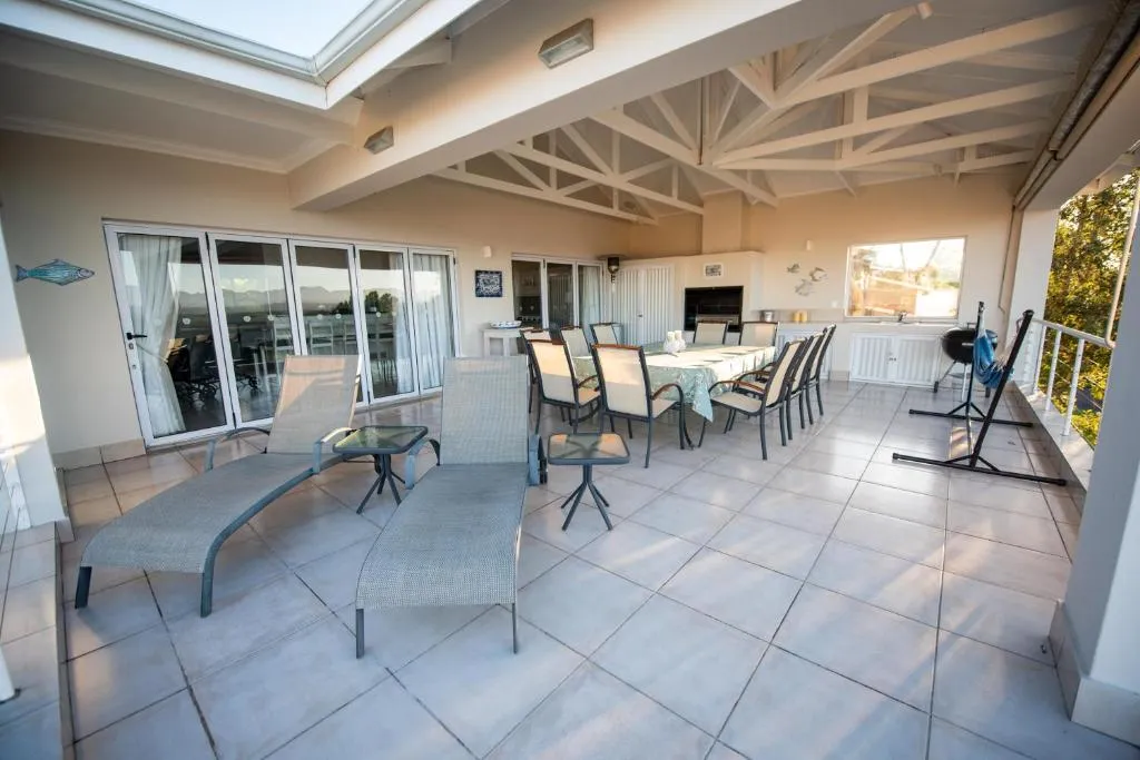 Covered upper-level entertainment deck with loungers, a long dining table and built-in braai