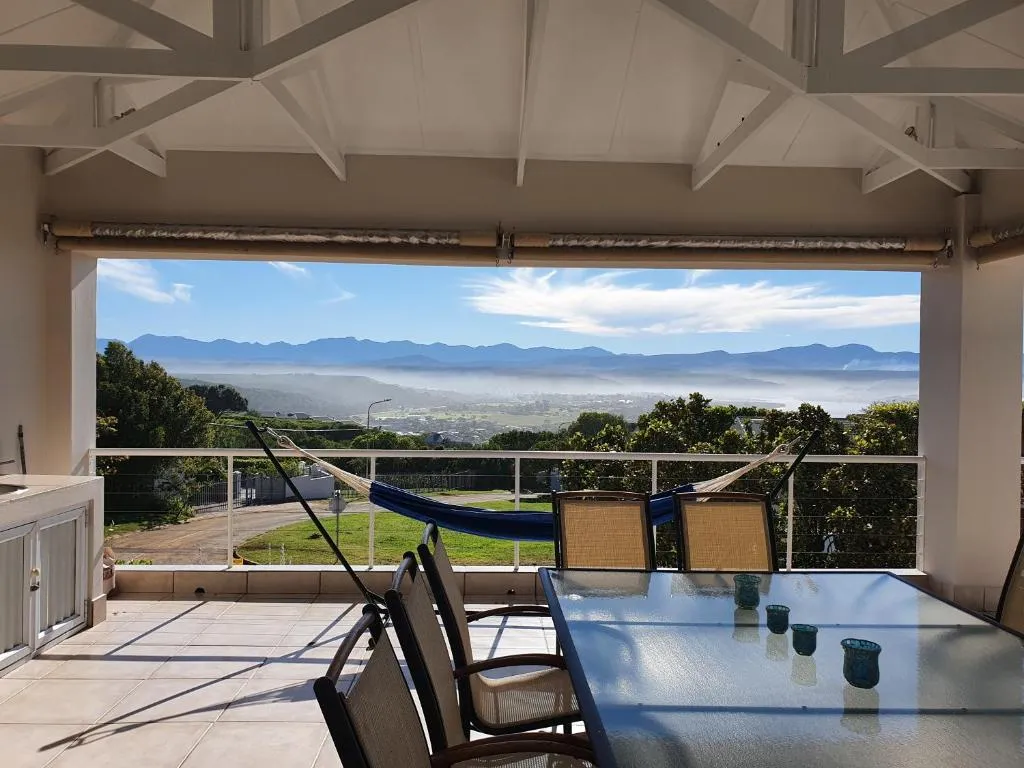 Covered patio with a hammock and dining table looking over a misty inland valley