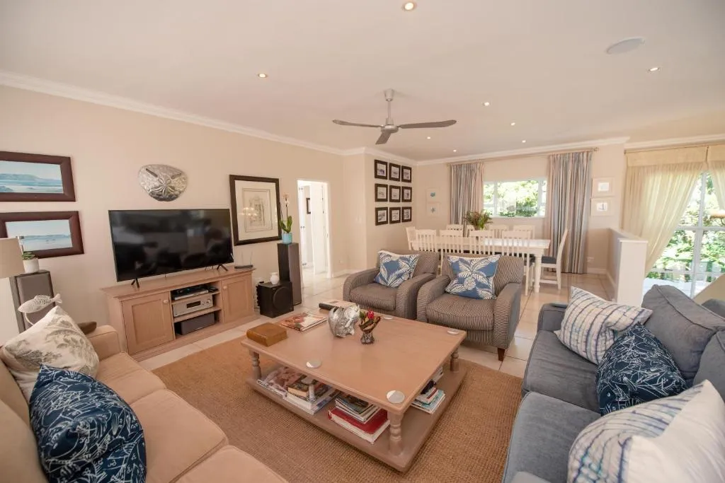 Open-plan living room with sectional sofas, a TV unit and a dining table beyond