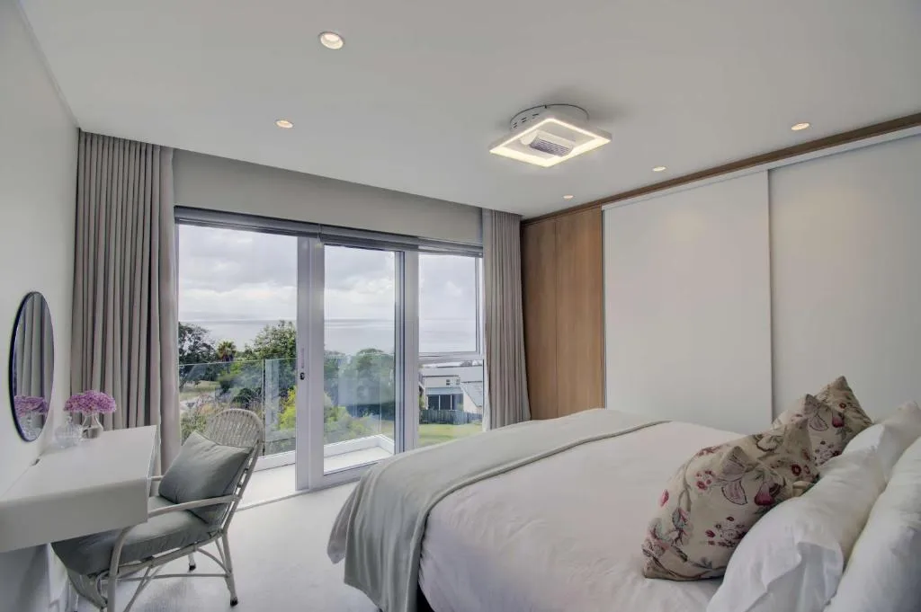 Main bedroom with sliding doors onto a private balcony overlooking the sea and rooftops