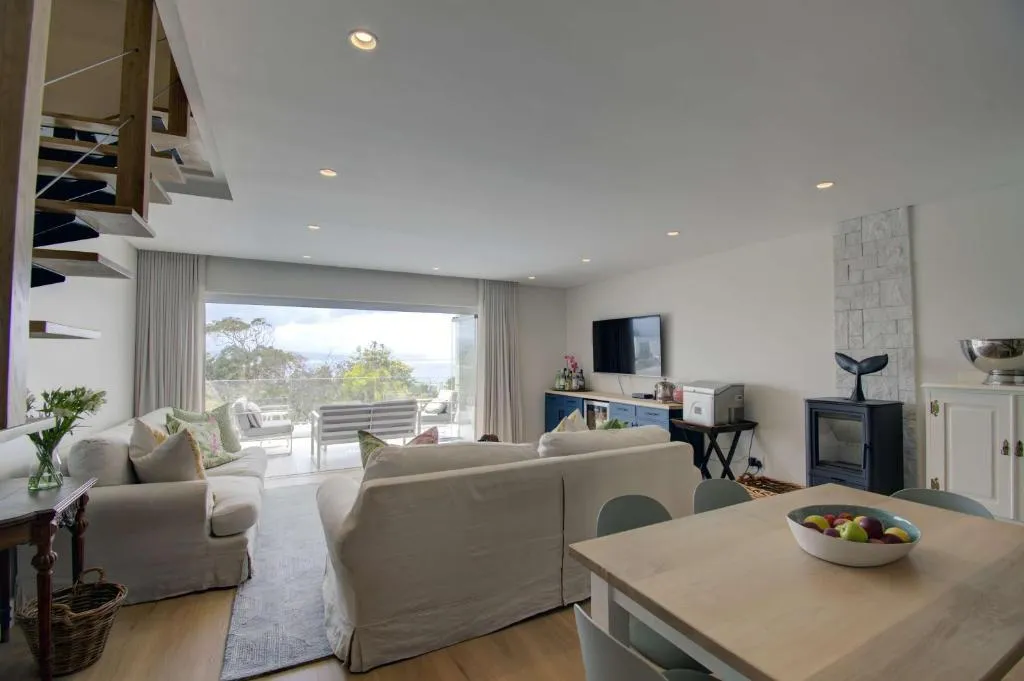 Double-volume living room with a spiral staircase, wood burner and sliding doors onto the balcony