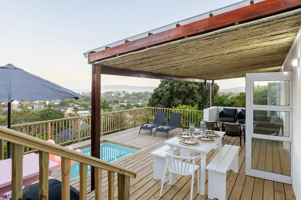 Covered deck with a dining table, sun loungers, a plunge pool and a distant sea view