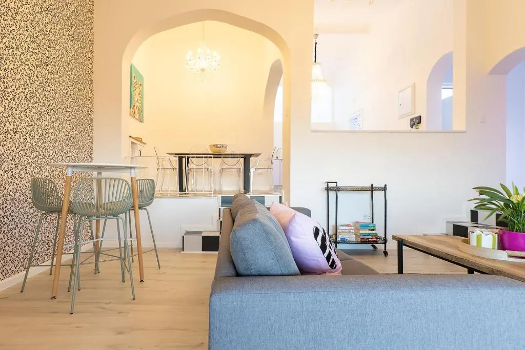 Open-plan lounge and dining area under an archway with a chandelier and bar-height table