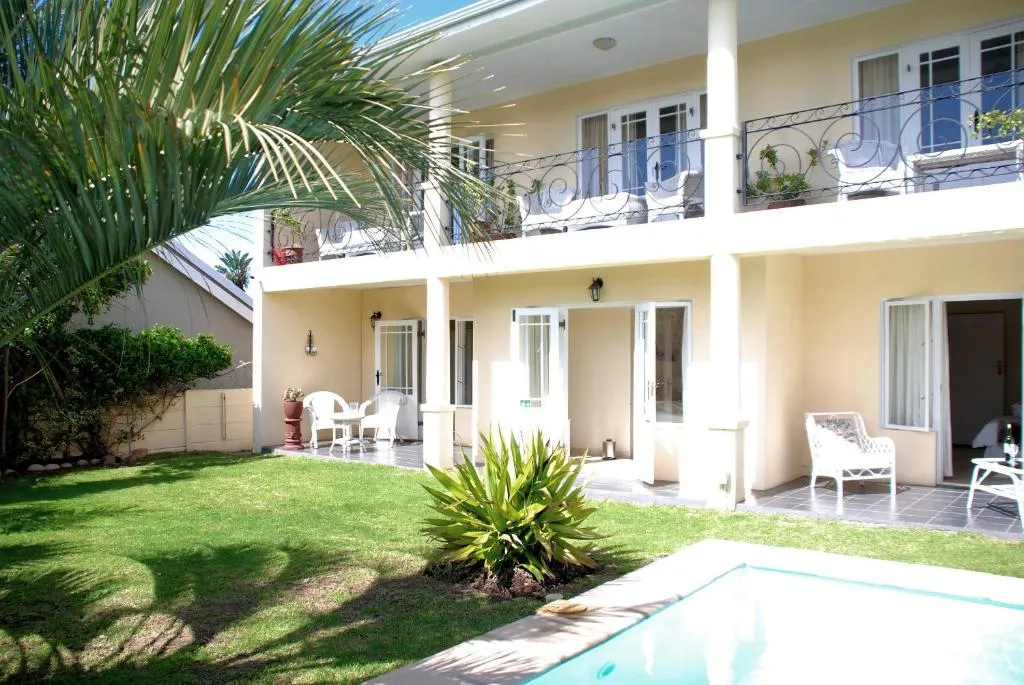 Rear view of the guest house with balcony seating and a poolside patio