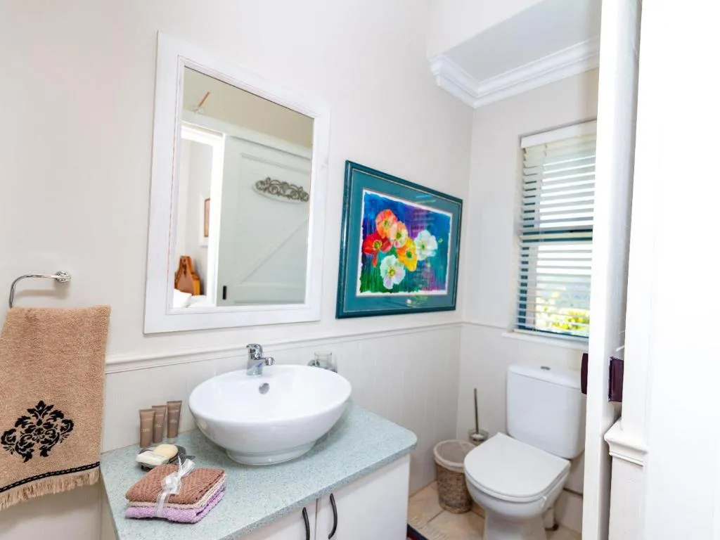 Guest bathroom with a vessel sink, floral artwork and a separate toilet nook