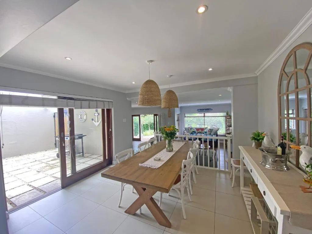 Dining area with woven pendant lights, leading through sliding doors to a paved patio and braai