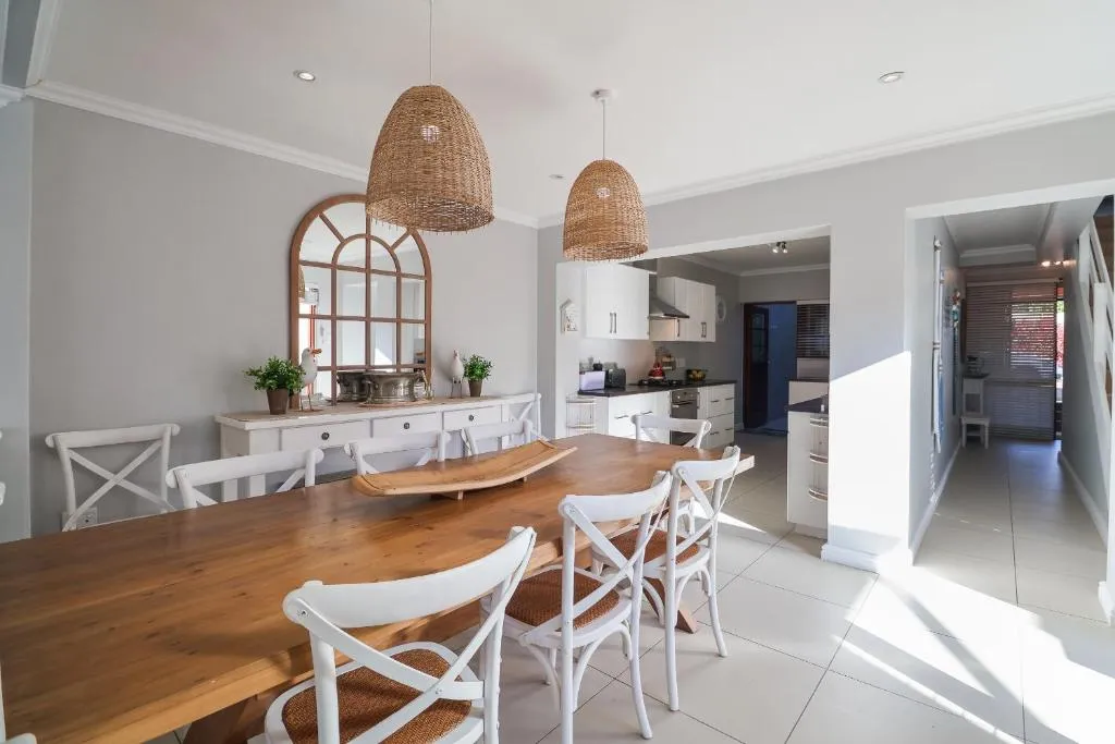 Dining table beside a white fitted kitchen with an extractor hood and gas stove