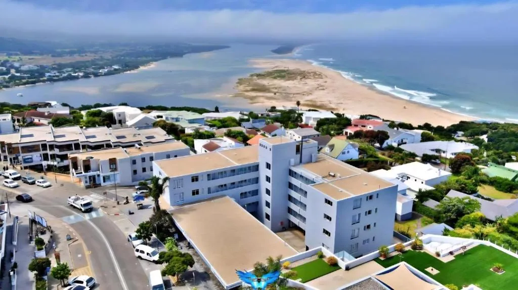 Aerial view of the white apartment block sitting between the lagoon mouth and the beach