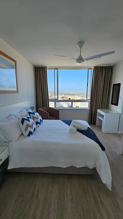Second bedroom with a queen bed, ceiling fan and an elevated window view over rooftops