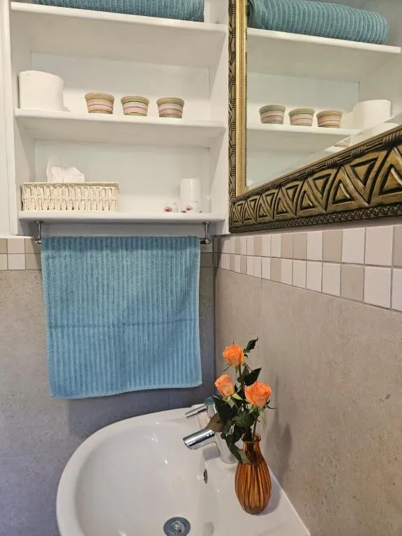 Bathroom shelf with towels and a pedestal basin below a gilt-framed mirror