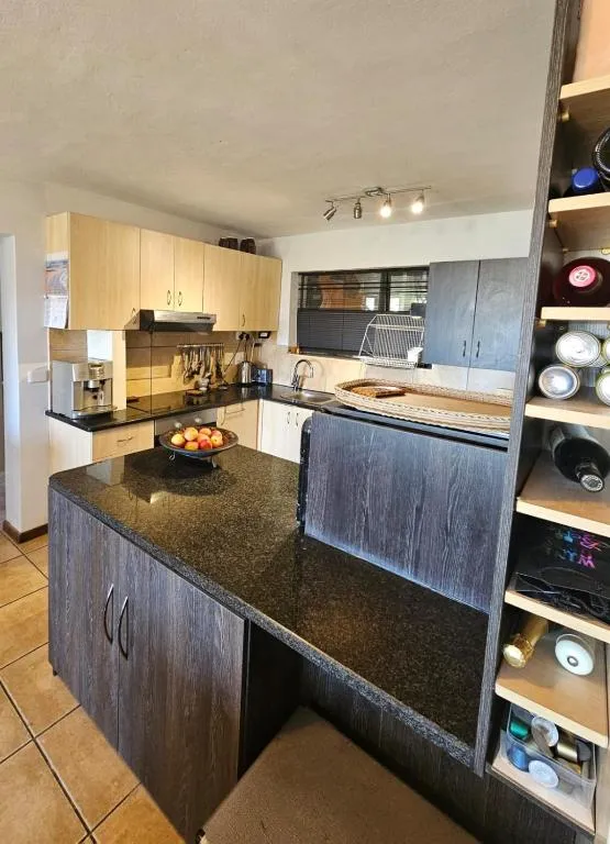 Kitchen with dark granite counters, wine rack shelving and light wood cabinetry