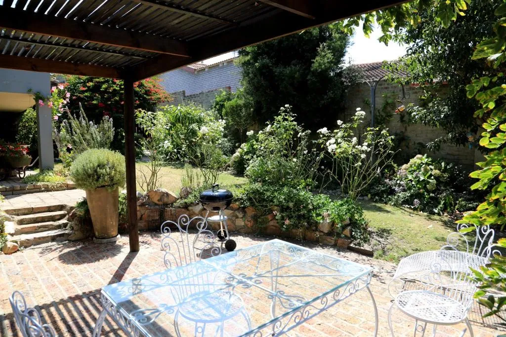 Walled garden with a Weber braai, pergola and wrought-iron outdoor dining table